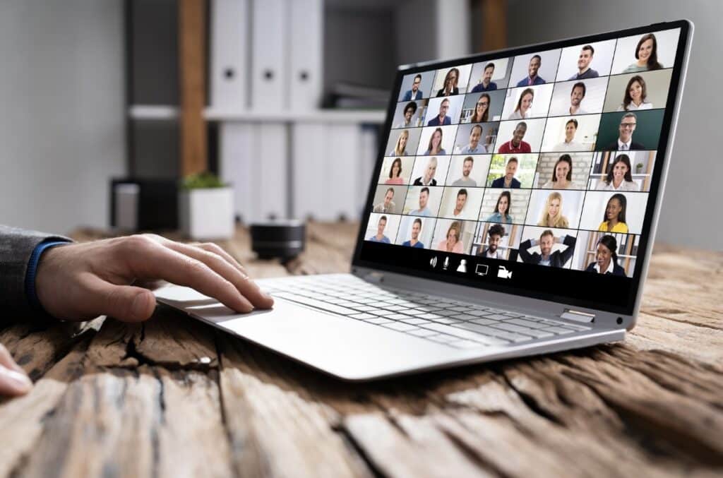 Laptop on desk with virtual meeting on the laptop screen.