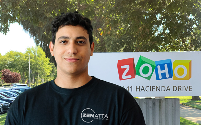 Eduardo Gonzalez, a developer at Zenatta Consulting in front of a sign with the Zoho logo on it